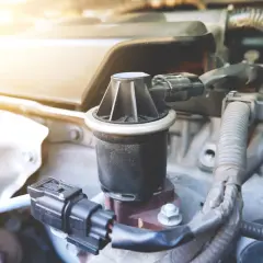 Dettaglio di un componente del motore, la valvola EGR, con cavi e tubi circostanti.