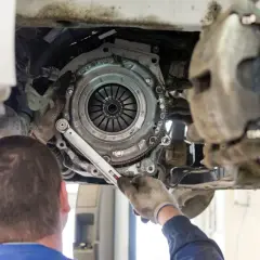 Meccanico lavora sulla frizione di un'auto. Scopri quanto costa cambiare la frizione per avere un'idea del preventivo.