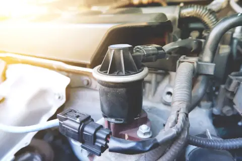 Dettaglio di un componente del motore, la valvola EGR, con cavi e tubi circostanti.