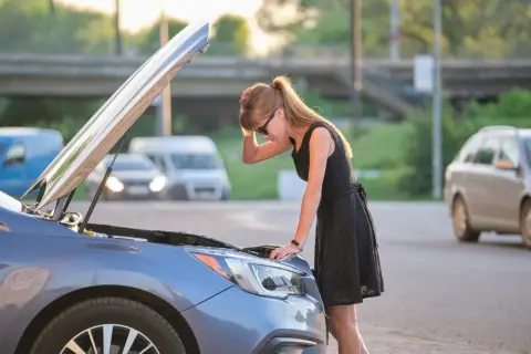 Donna preoccupata guarda il motore della sua auto, il motore diesel gira ma non parte.
