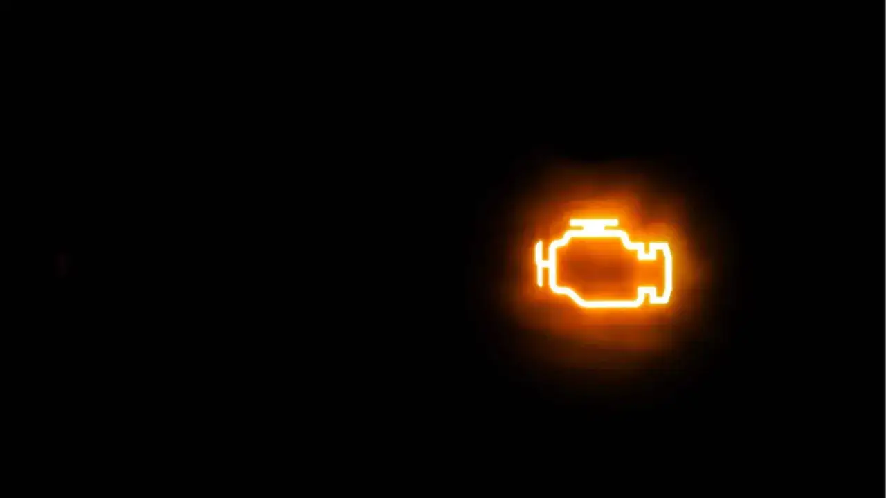 Spia motore accesa, un segnale luminoso arancione su sfondo nero che indica un problema.